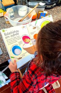 Child reading the book Mum and Me in the Kitchen by DK Publishing, open on the Star Cookies recipe, with ingredients on the counter in the background