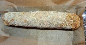 Raw chicken roll coated with breadcrumbs on a clean sheet of parchment paper, ready to go into the oven at 180 degrees