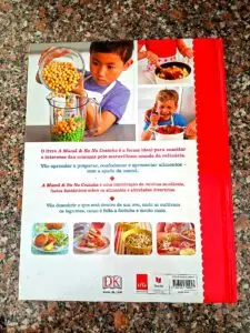 Back cover of the book “Mom & Me in the Kitchen” featuring photos of children cooking, descriptive text in Portuguese, and four recipe thumbnails, set against a granite countertop.