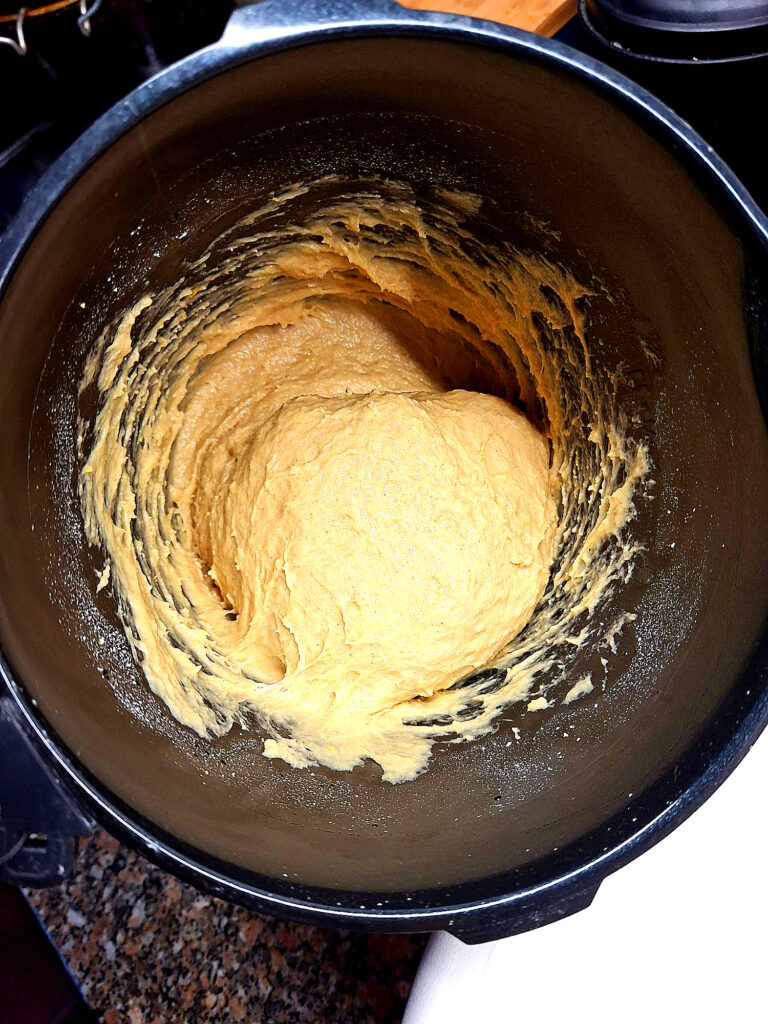 White bowl with thick, smooth sweet dough on a granite countertop.