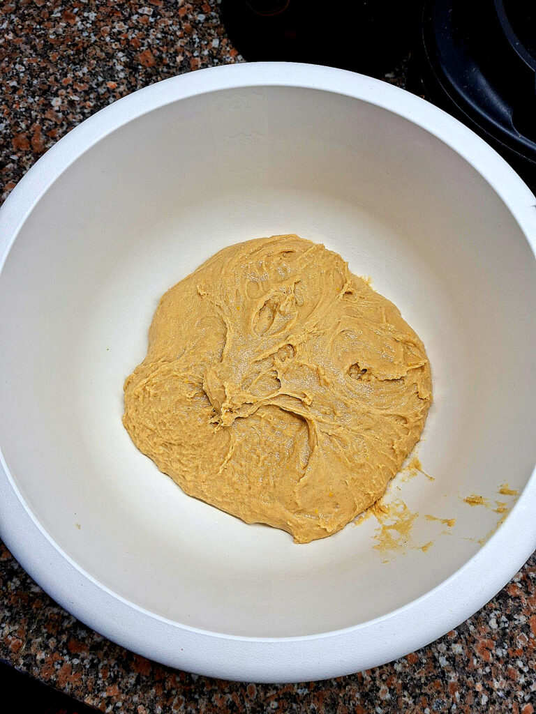 Taça branca com massa de pão doce de cor amarelada e textura elástica, pronta para levedar.