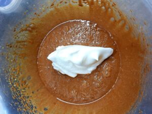 Bowl with chocolate mixture and a portion of whipped egg whites on top, ready to be folded.
