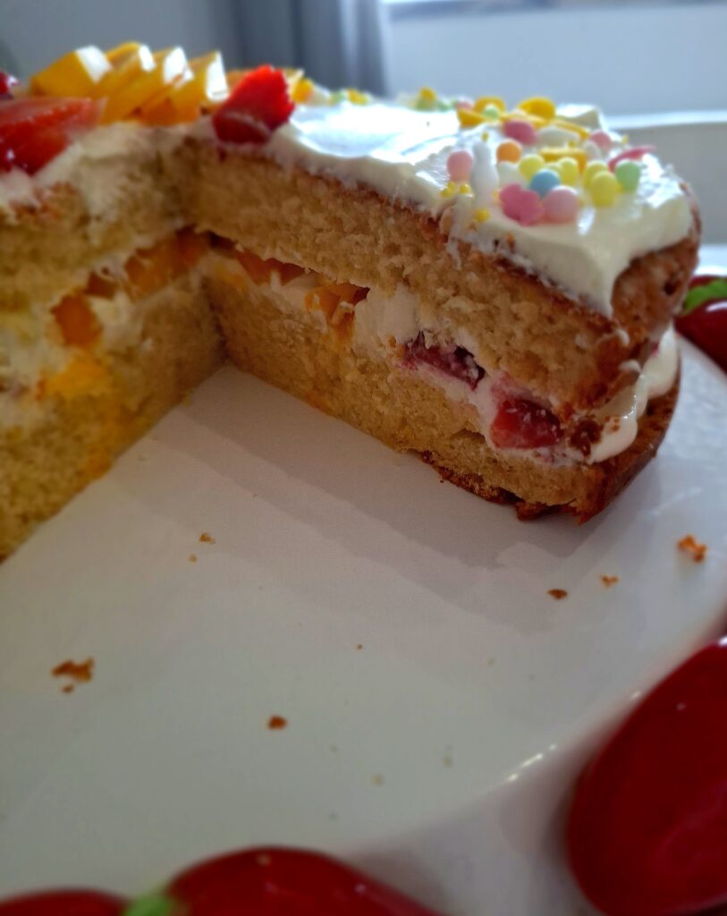 Interior do bolo de limão com mascarpone cortado mostrando recheio de mascarpone com morango e pêssego entre duas camadas de pão de ló fofo