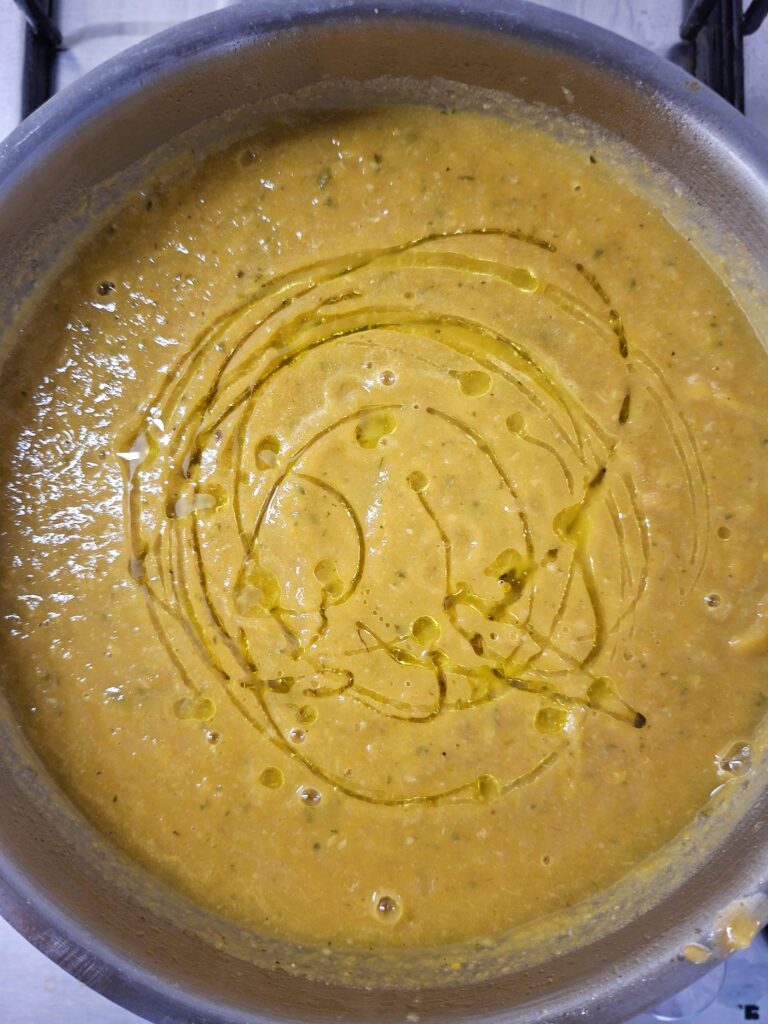 Panela com creme de legumes espesso e cremoso, finalizado com um fio de azeite em espiral.