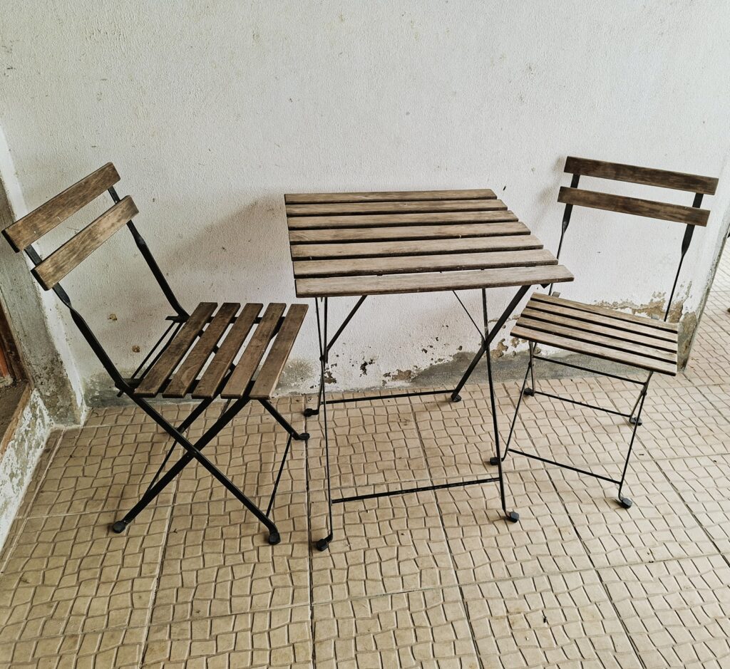 Mesa e duas cadeiras de madeira com estrutura metálica, no seu estado original, sem pintura.