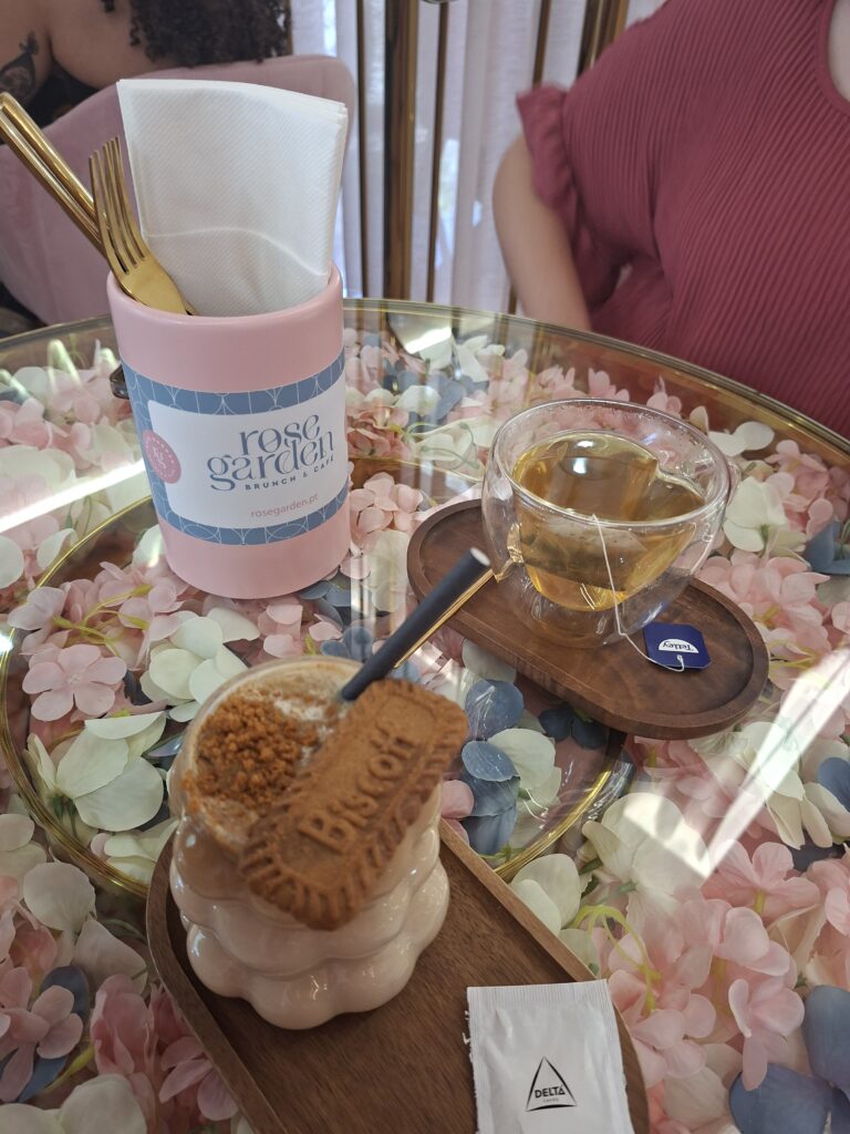 Hot tea and a latte caramelserved on a glass table decorated with pink, white and blue petals.