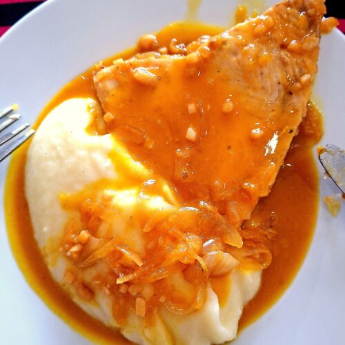 Prato com puré de batata cremoso e espadarte coberto com molho rico e brilhante, pronto a servir.