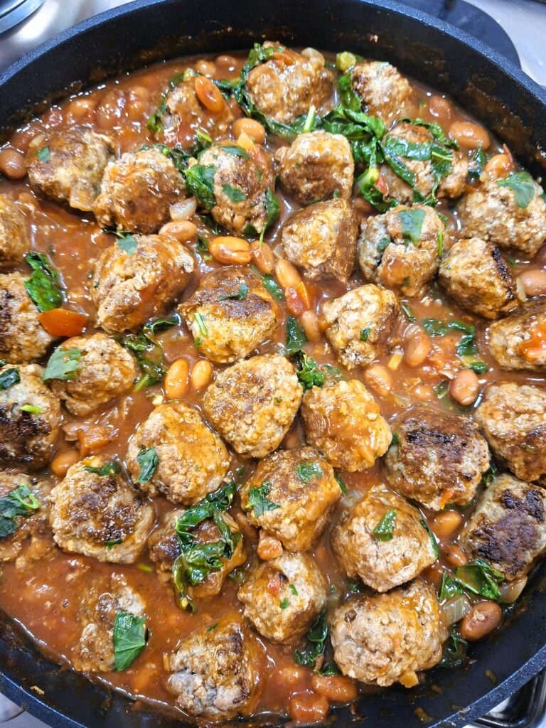 Almôndegas cozinhadas em molho de tomate com feijão, kale e legumes.